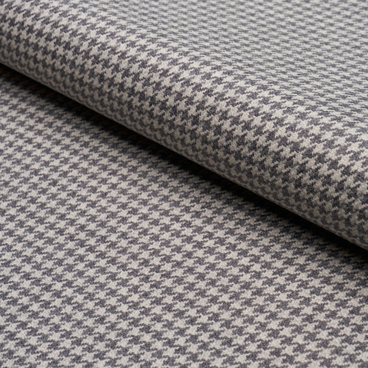 Grey & white houndstooth wool blend fabric, rolled bolt; classic tailored textile for coats, jackets, or upholstery.
