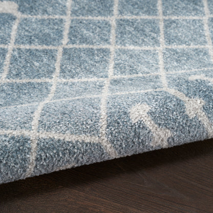 Blue shag rug with white grid pattern, thick plush pile, corner resting on dark wooden floor.