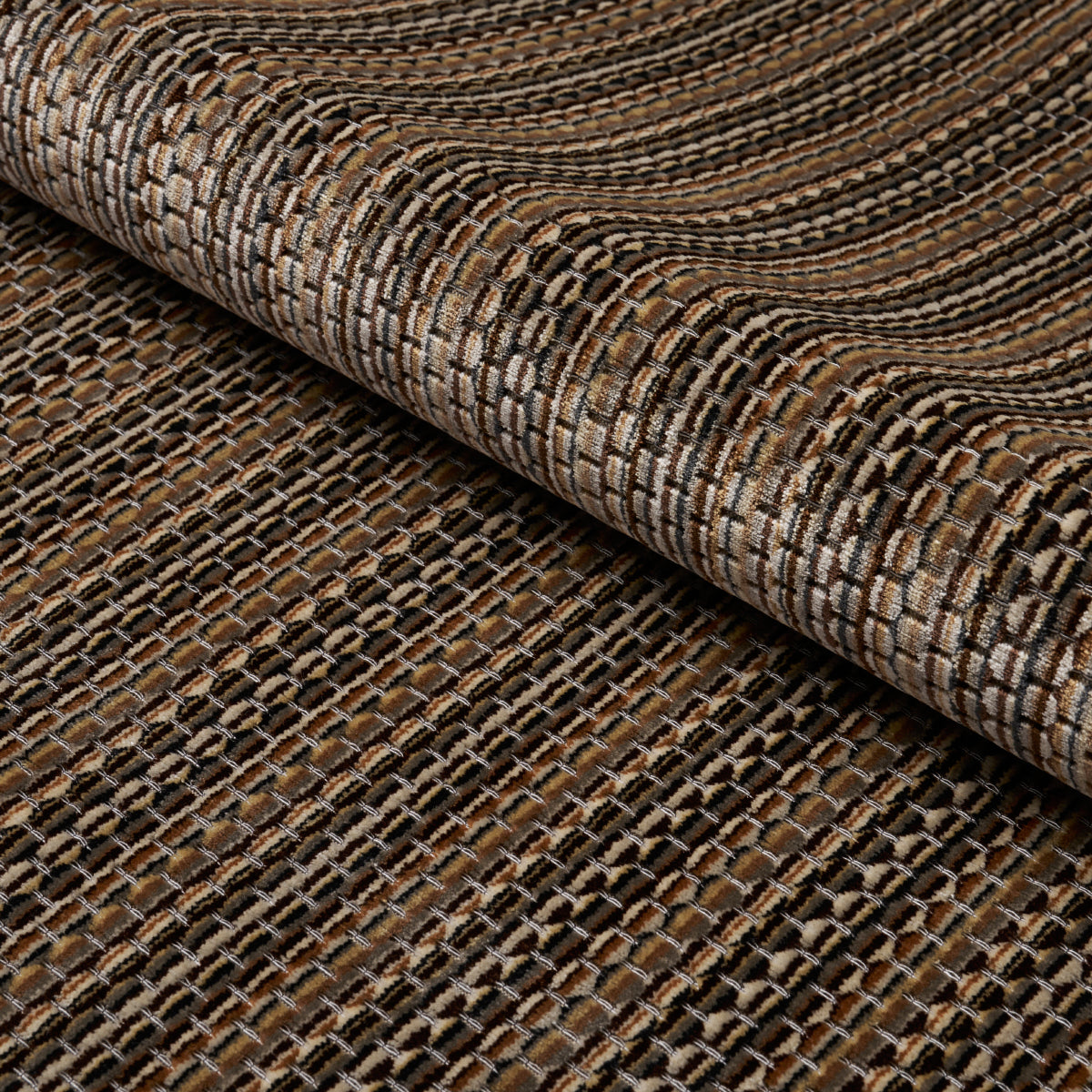 Brown and beige woven rug with a textured striped pattern, rolled at the edge to show chunky weave.
