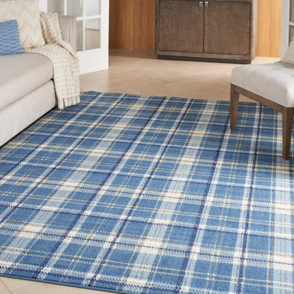 Blue plaid area rug on light wood floor in a cozy living room with gray sofa and dark wood cabinet.