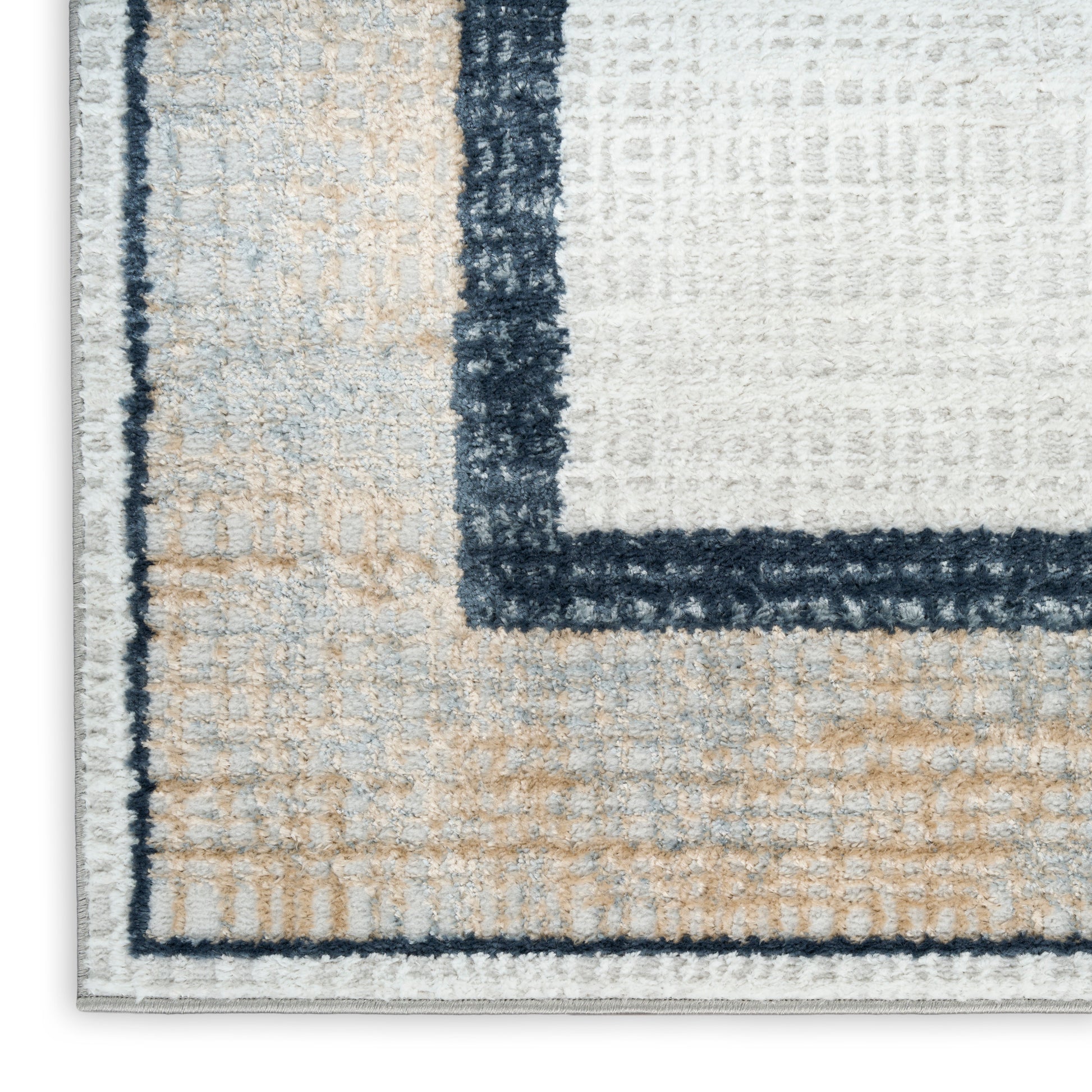 Close-up of a rectangular plush tufted rug with beige, white & navy borders in a geometric pattern.