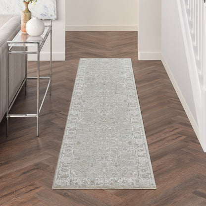 Light gray patterned 10' runner rug on a dark herringbone hallway floor, with a chrome glass-top console table nearby.