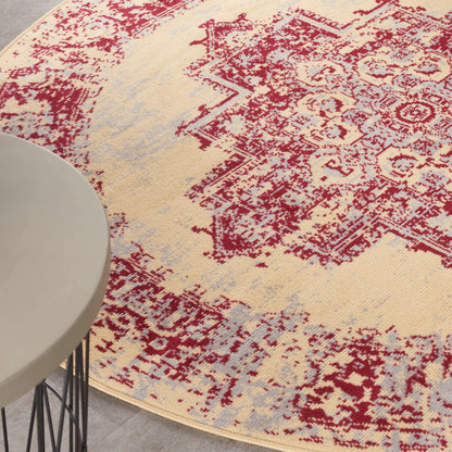 Round beige distressed oriental rug with red medallion pattern and pale blue accents under a white round table.