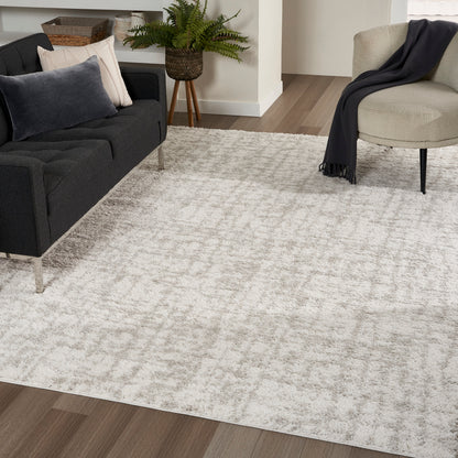 Beige textured rug on wood floor in modern living room with dark gray sofa, beige chair, and potted plant.