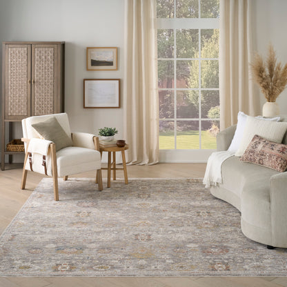 Neutral living room with beige sectional, light wood chair, woven cabinet, framed art, big window, patterned rug.