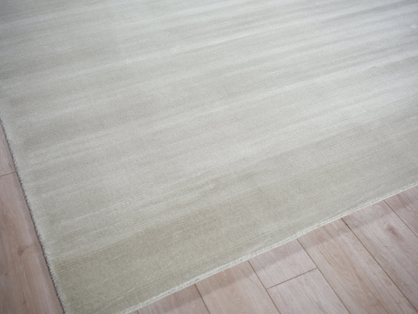 Cream beige flat-weave rug with soft texture on light wood floor; minimalist home decor.