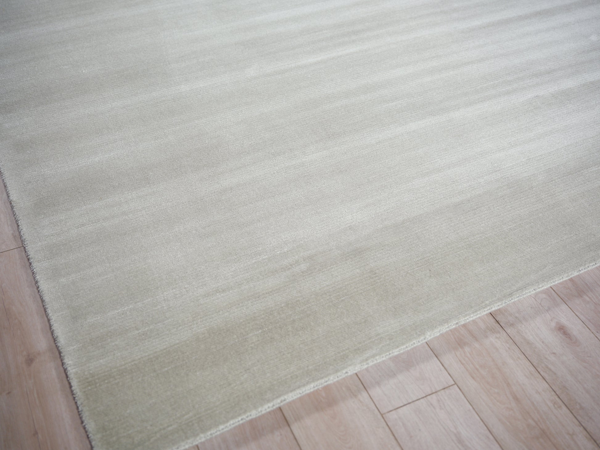 Cream beige flat-weave rug with soft texture on light wood floor; minimalist home decor.
