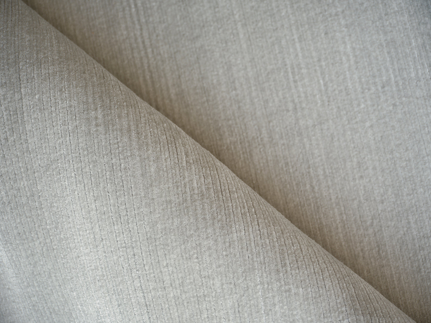 Light gray ribbed fabric close-up with diagonal fold and soft texture.