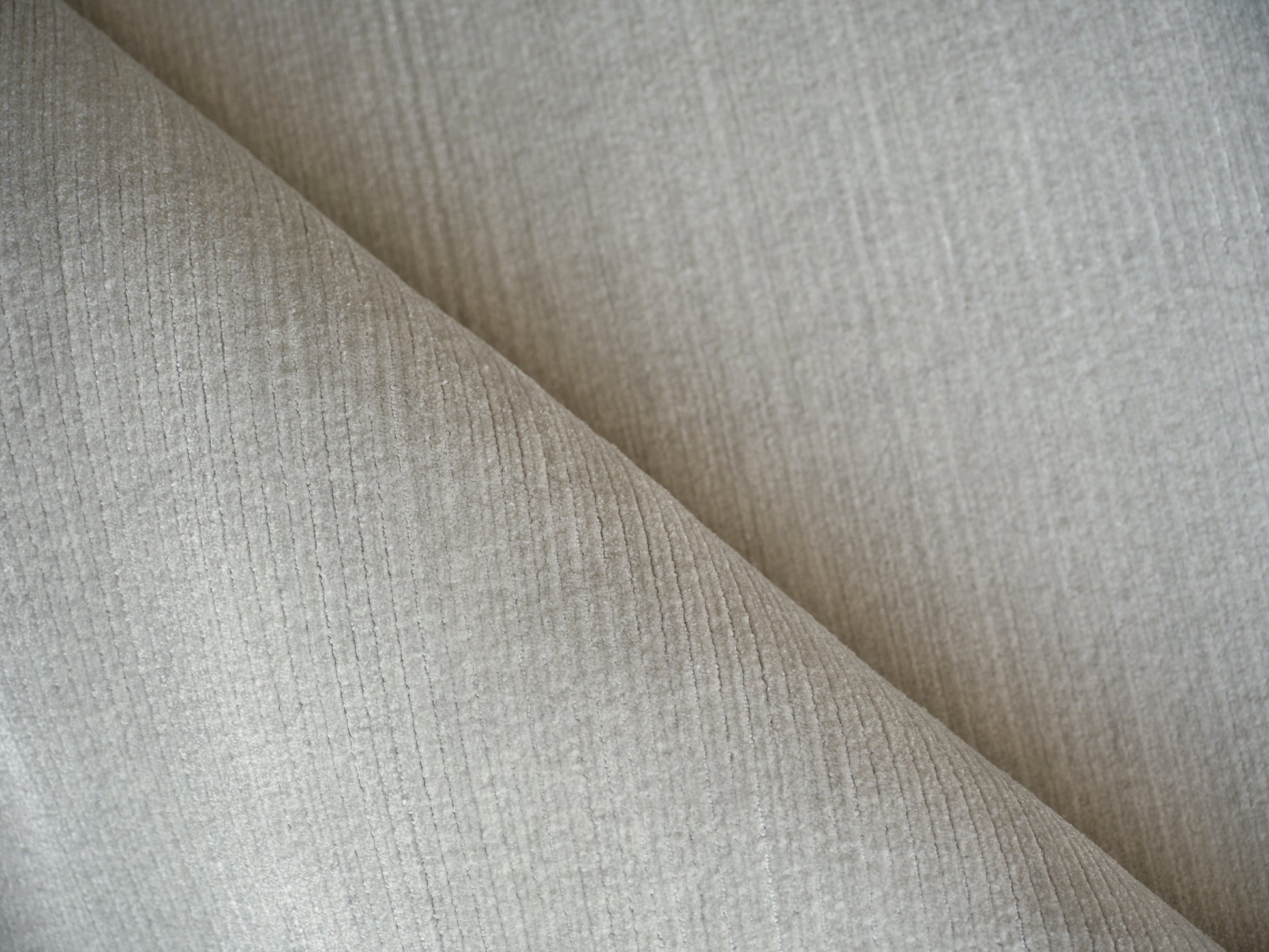 Light gray ribbed fabric close-up with diagonal fold and soft texture.
