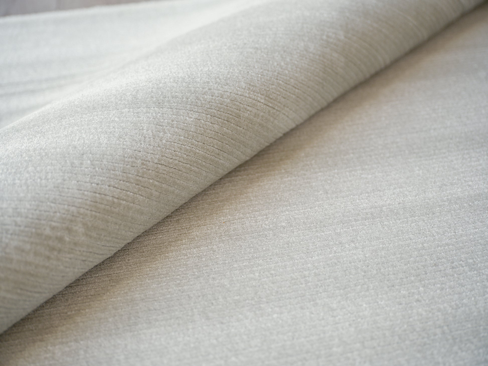 Light gray-beige ribbed fabric roll, soft brushed texture for upholstery or drapery.