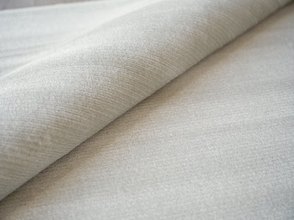 Light beige textured fabric with soft nap, rolled fold; close-up upholstery textile.