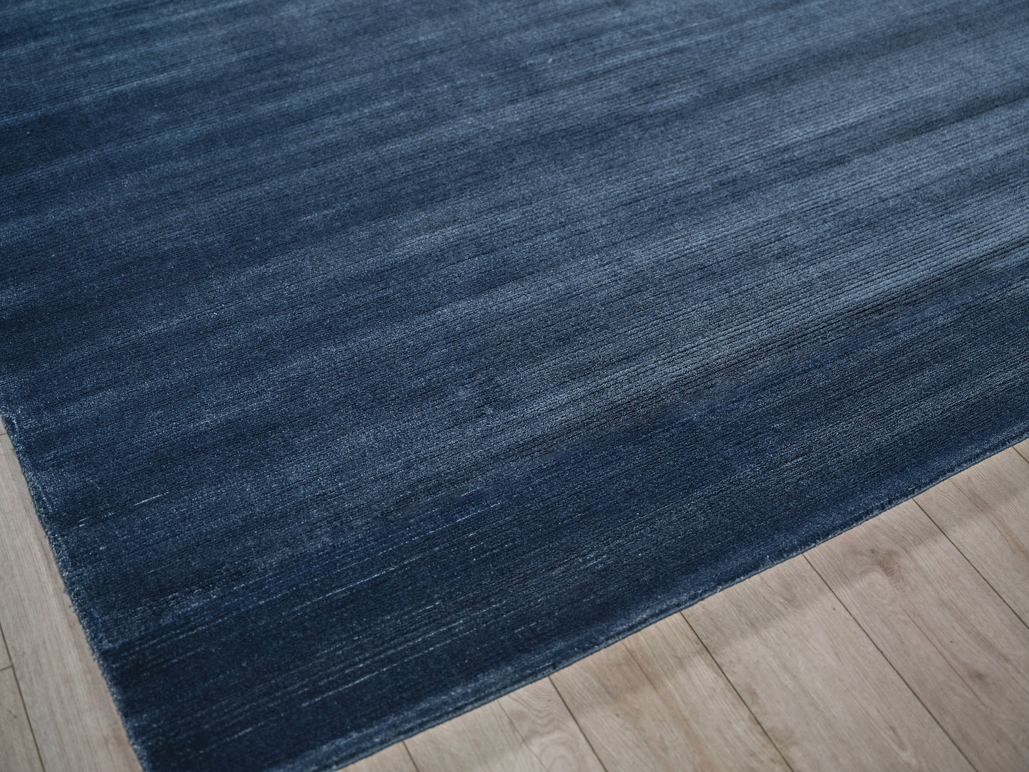 Deep blue gradient area rug with subtle striped texture on light wood flooring.