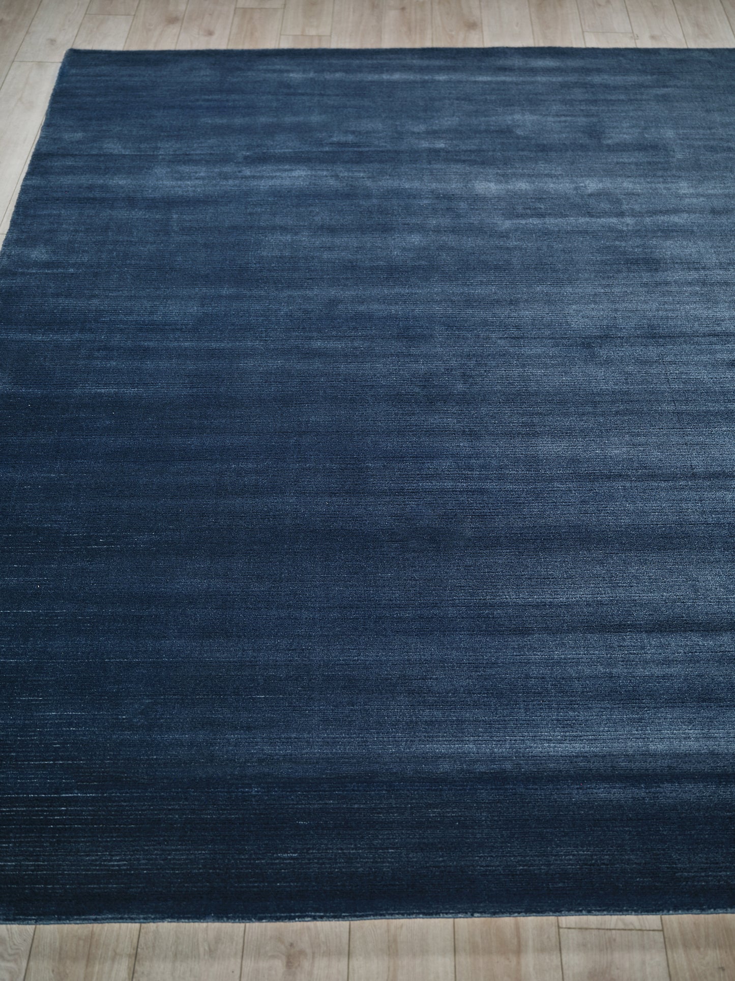 Rectangular dark blue rug with subtle distressed texture on light wood floor.