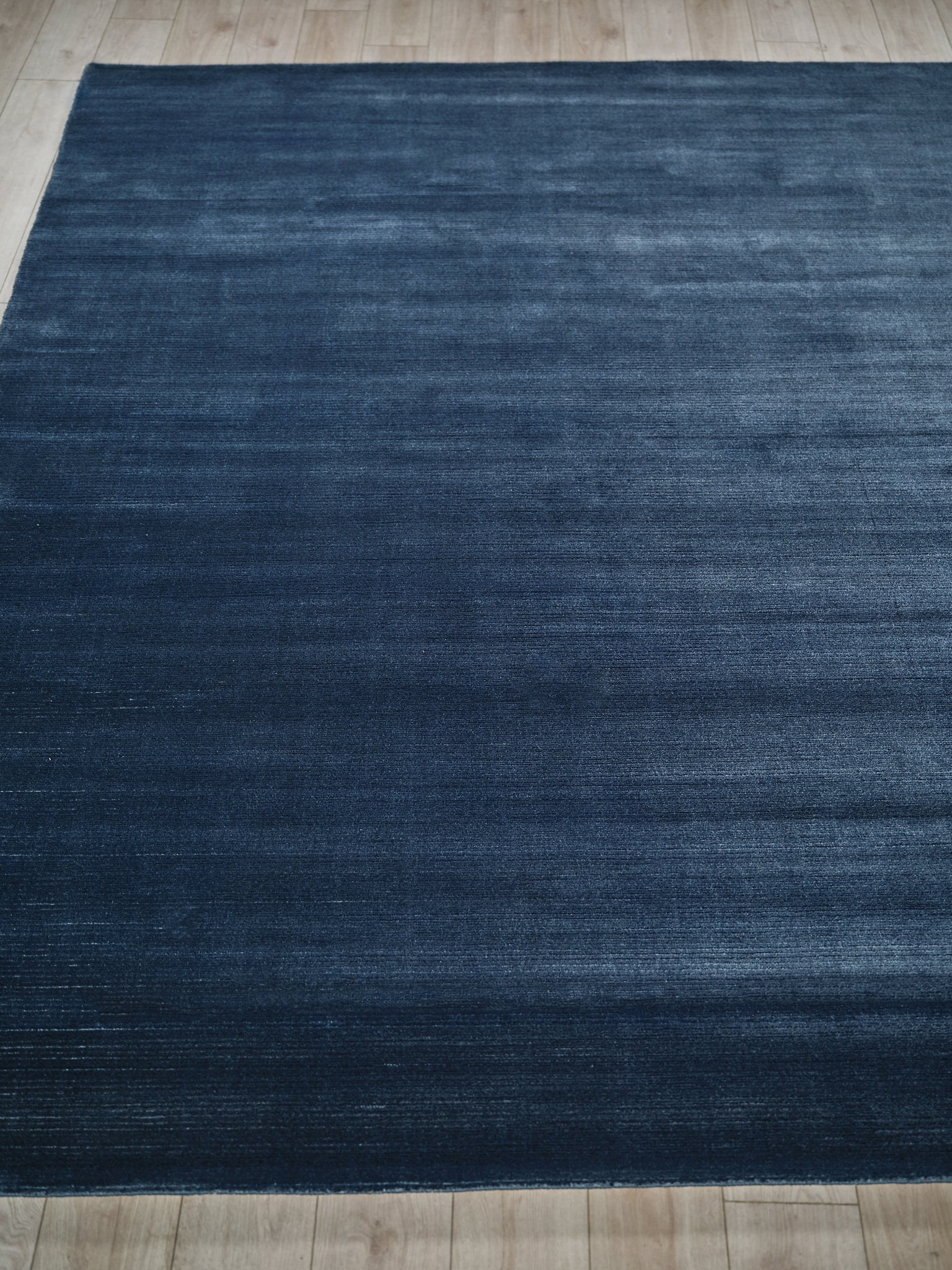 Rectangular dark blue rug with subtle distressed texture on light wood floor.