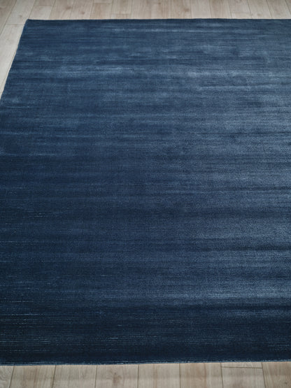 Rectangular dark blue rug with subtle distressed texture on light wood floor.