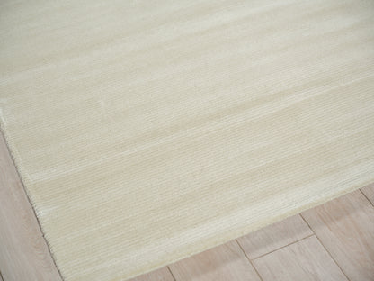 Cream rectangular area rug with a soft ribbed texture on a light wood floor.