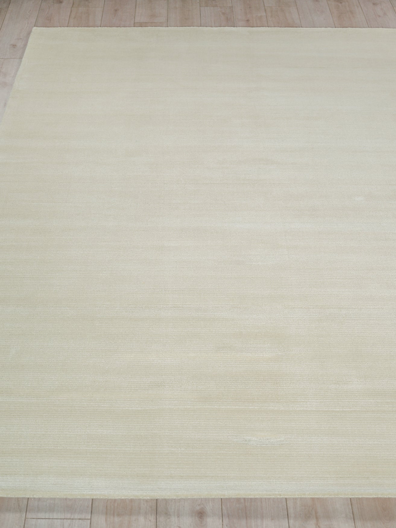 Cream-beige rectangular area rug with subtle horizontal texture, placed on light wood floor.
