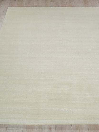 Cream-beige rectangular area rug with subtle woven texture on light wood floor.