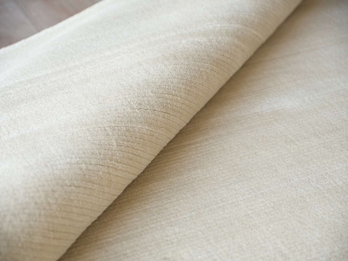 Beige velvet fabric roll with soft nap, plush texture for upholstery or curtains.