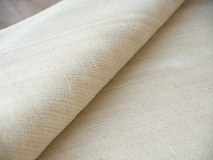 Beige velvet fabric roll with soft nap, plush texture for upholstery or curtains.