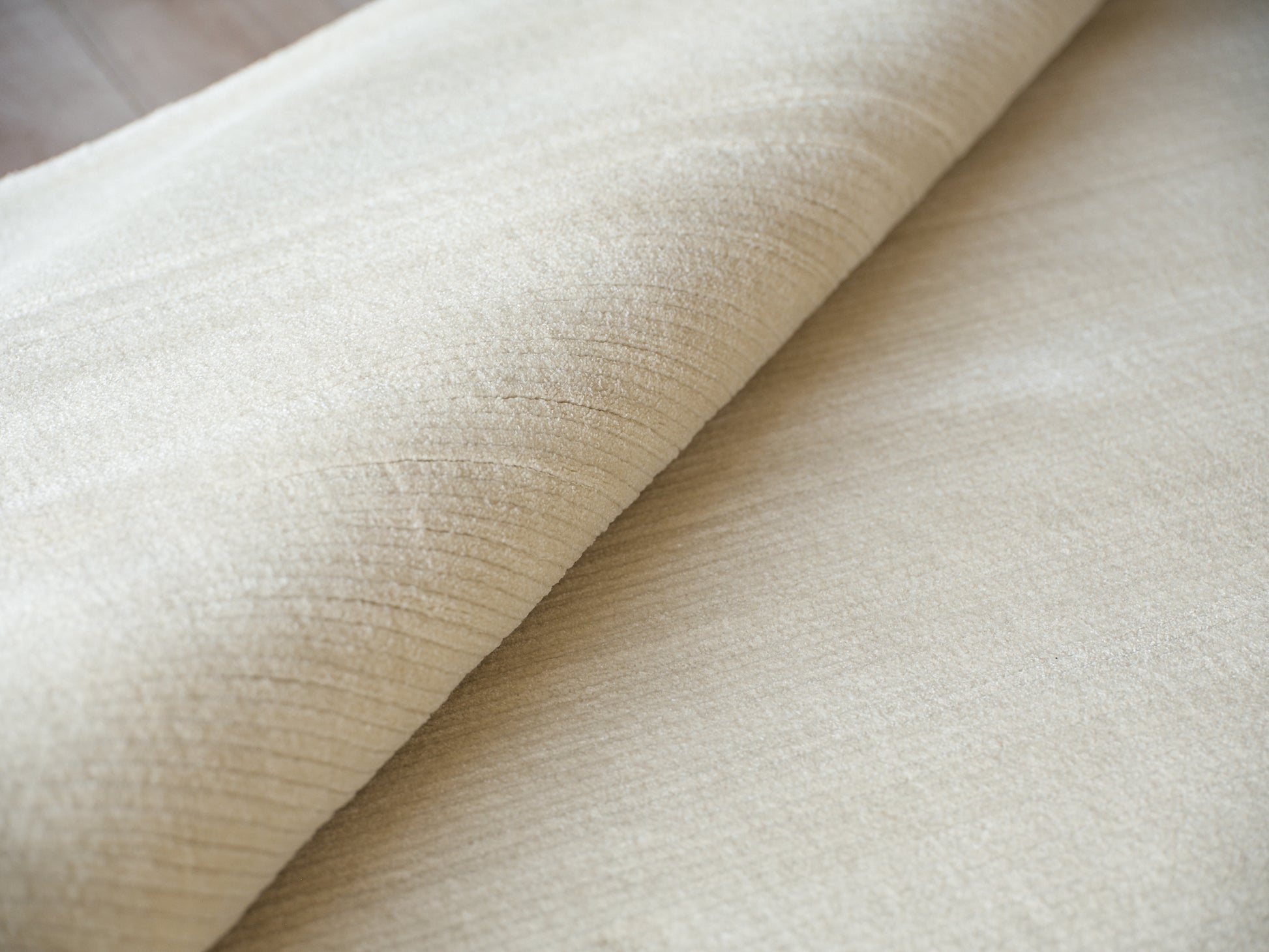 Beige velvet-like fabric roll with soft nap and subtle texture, suitable for upholstery or drapery.
