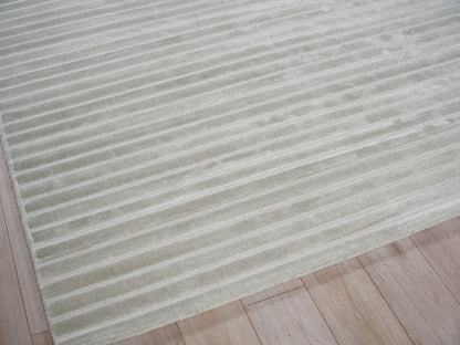 Creamy beige rug with uniform ribbed stripes on a light wood floor.