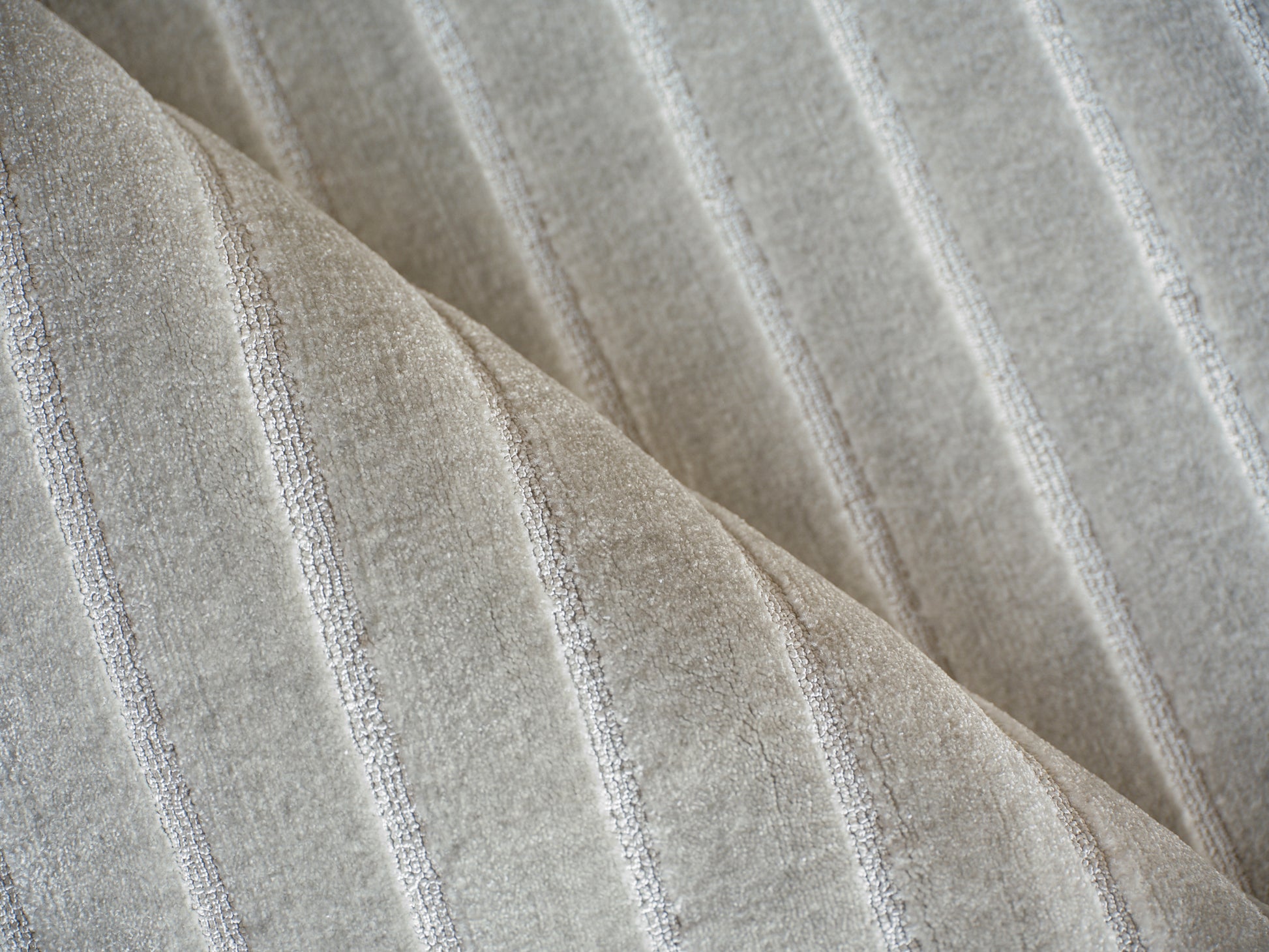 Beige rug with a subtle silver striped pattern and soft pile; hand loomed indoor rug.