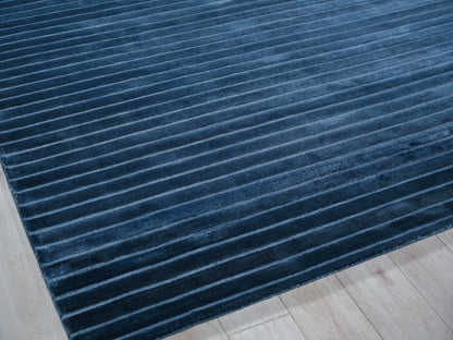 Rectangular deep blue ribbed plush rug on light wood floor, modern contemporary style.
