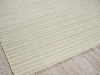 Beige ribbed area rug, low-pile with horizontal grooves, laid on light wood flooring.