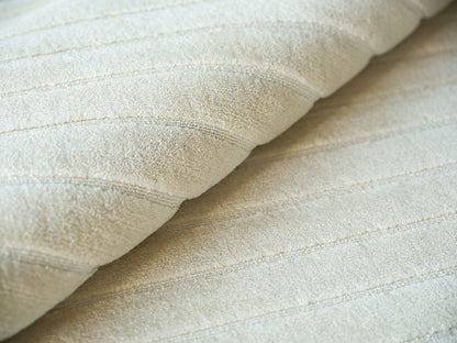 Cream beige hand loomed rug with subtle stitched stripes, folded for display, 2' x 3'.
