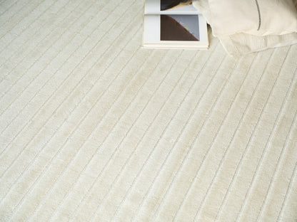Cream striped rug with a soft beige cushion in the top-right corner and an open photo book.