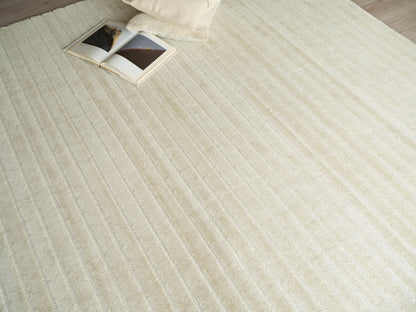 Cream textured rug with parallel stripes; open magazine and a pale pillow at the corner.