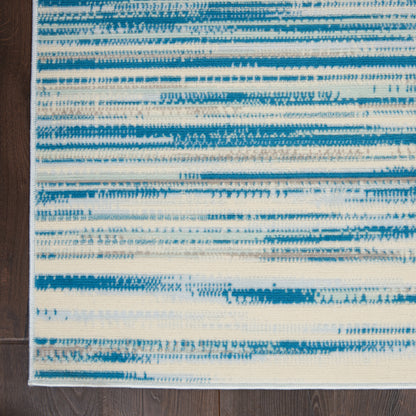 Rectangular blue and white abstract striped area rug with brushstroke horizontal lines on dark wood floor.