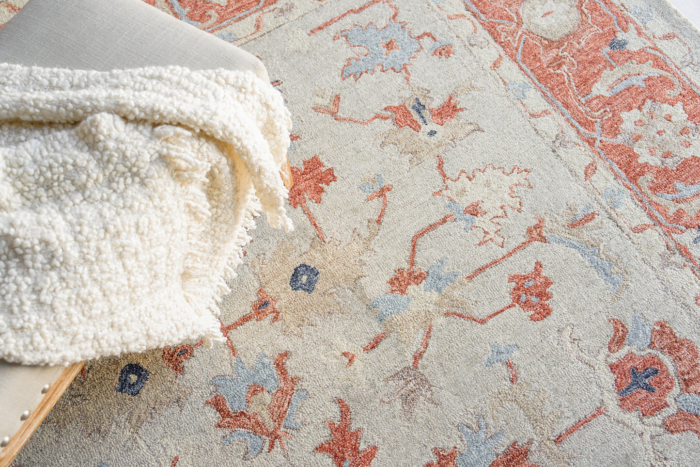 Beige oriental rug with red and blue floral motifs; plush, cozy texture.