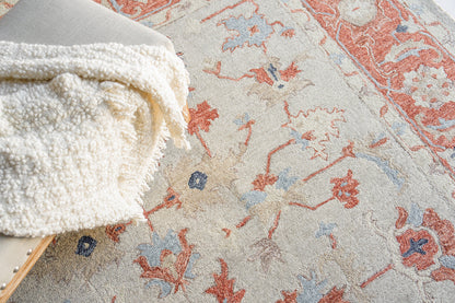 Beige oriental rug with red and blue floral motifs; plush, cozy texture.