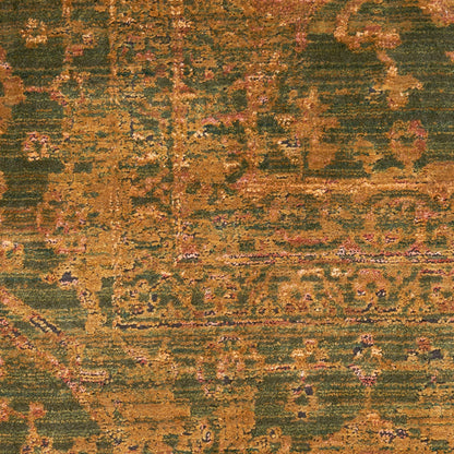 Close-up of a distressed olive-green and mustard oriental rug with pink highlights and ornate floral-geometric motifs.