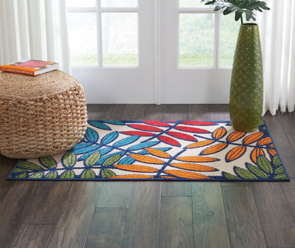 Woven cotton runner rug with blue, green and orange tropical leaves on white, dark blue border, in a bright doorway.