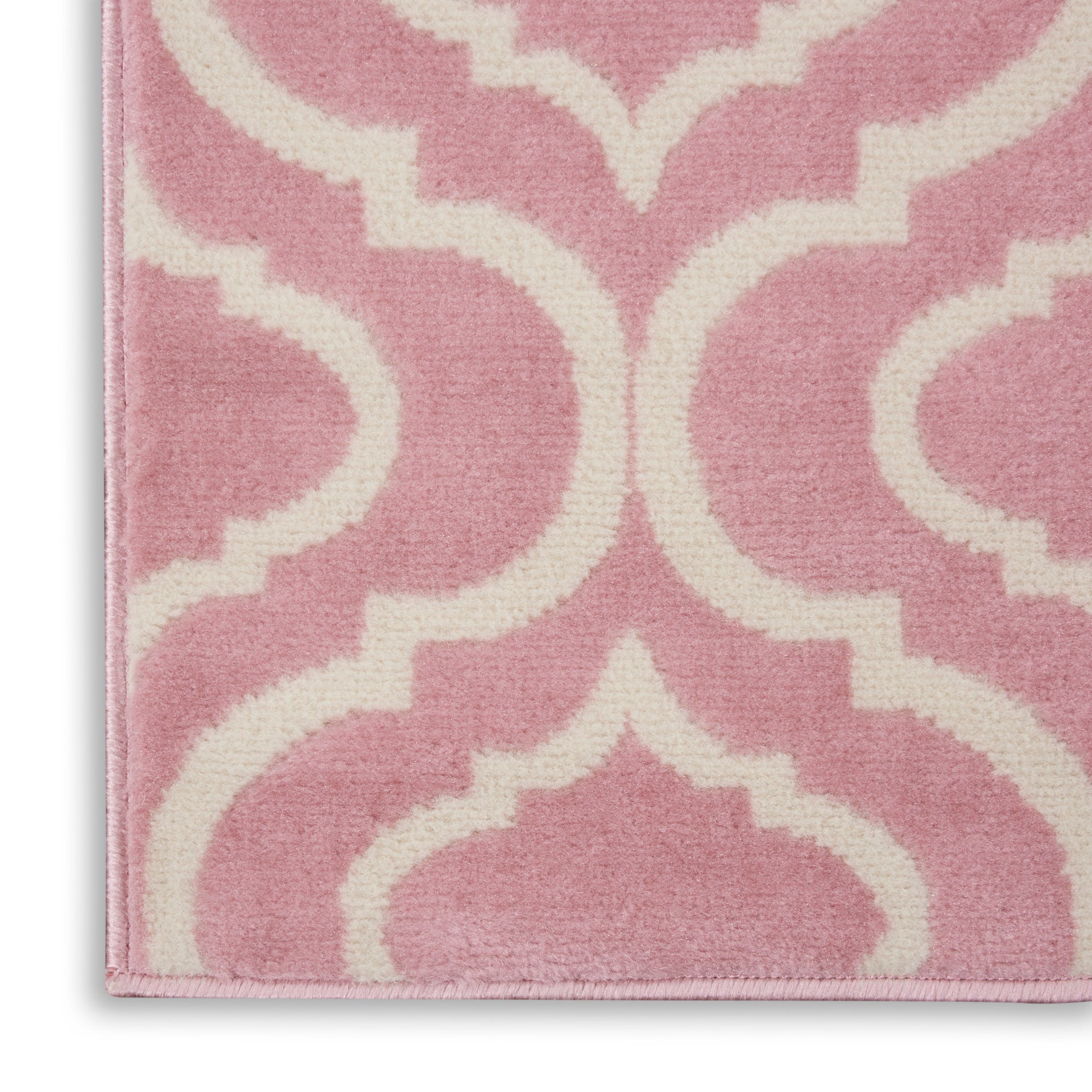 Pink and white plush rug with a geometric trellis pattern; close-up corner view.