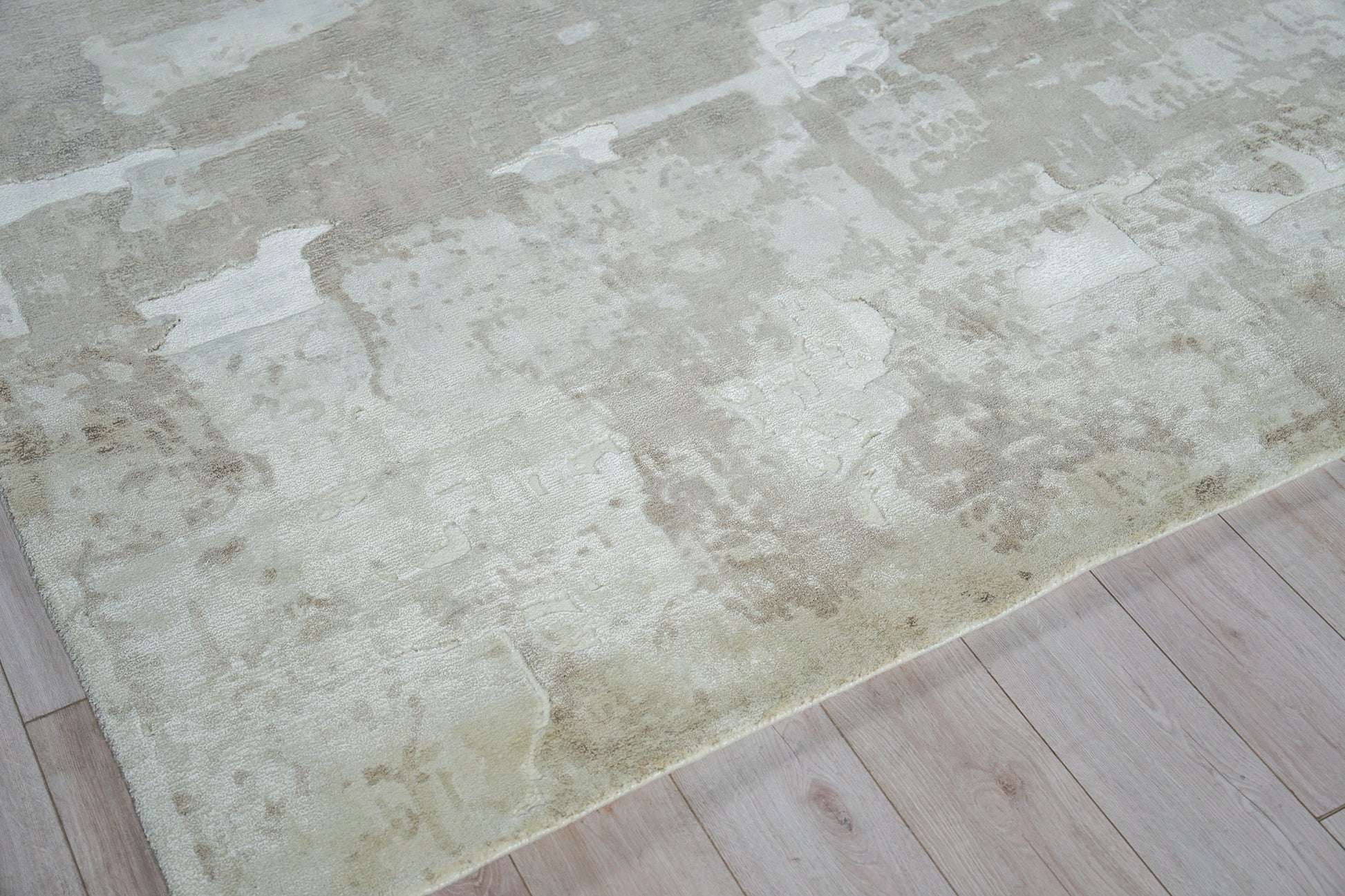 Cream-beige distressed area rug on light wood floor, hand loomed.