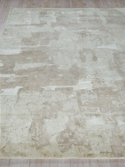 Neutral cream and beige distressed area rug with patchwork pattern on light wooden floor.