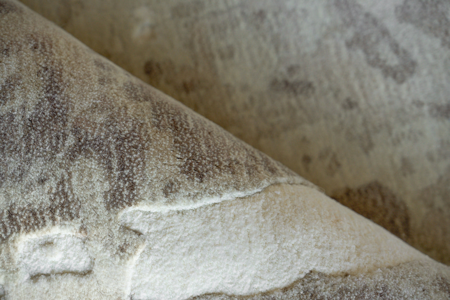Soft, plush brown-beige rug with a mottled pattern and a folded edge.