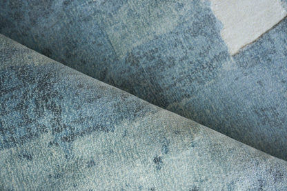 Blue denim-style rug with faded patches, folded to reveal a soft, textured weave; hand loomed.