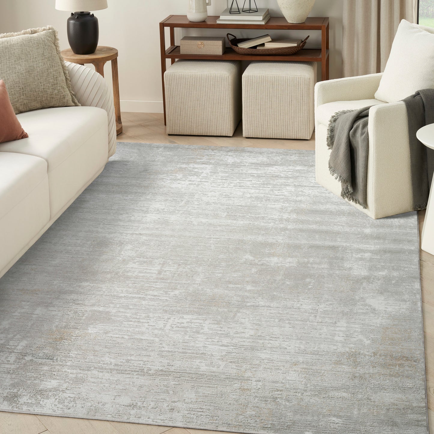 Soft gray distressed area rug in a modern living room with cream sofa, beige ottomans & wooden console table.