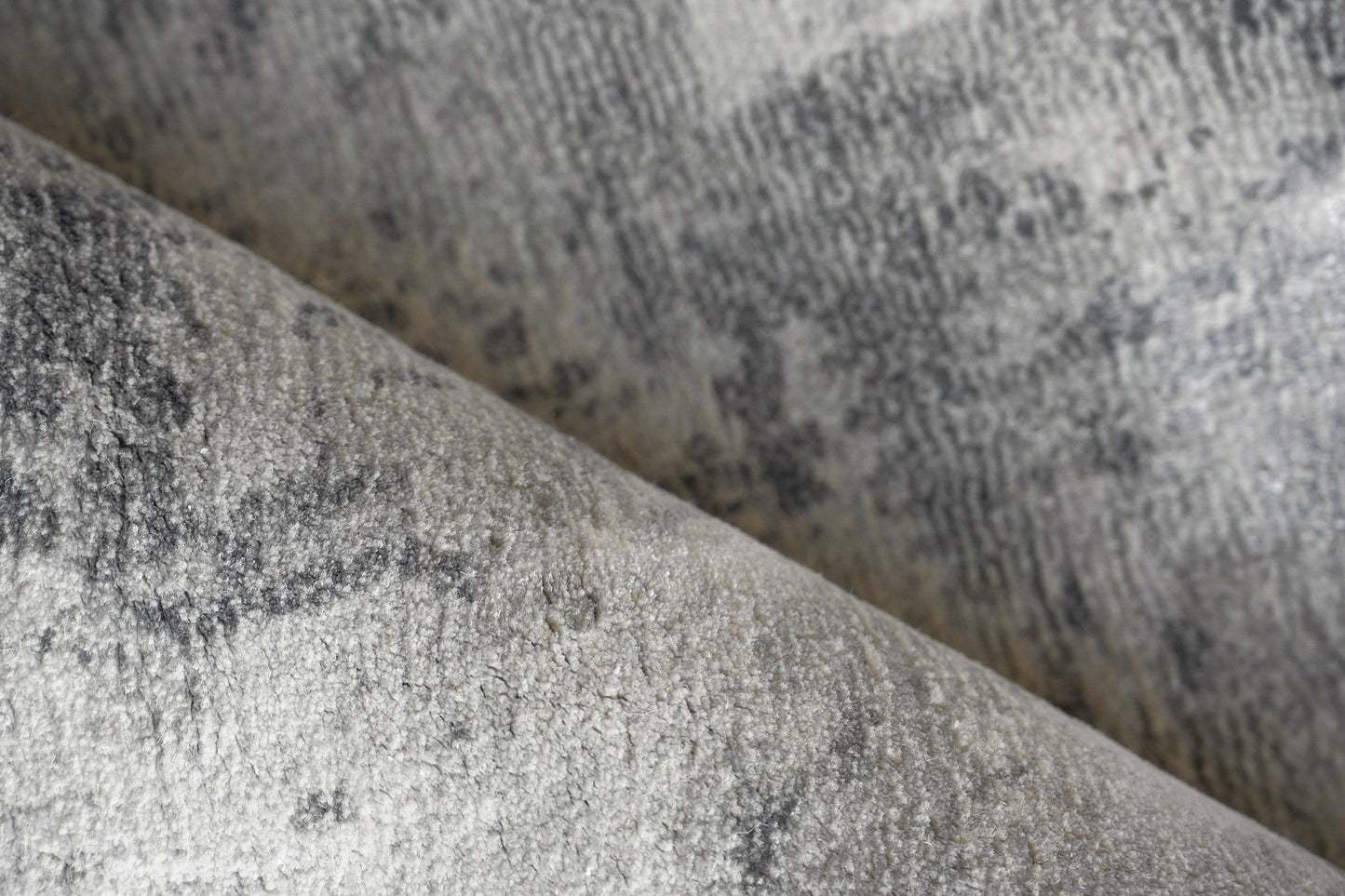 Close-up of plush gray velvet-like rug pile with a mottled pattern on an indoor hand-loomed rug.