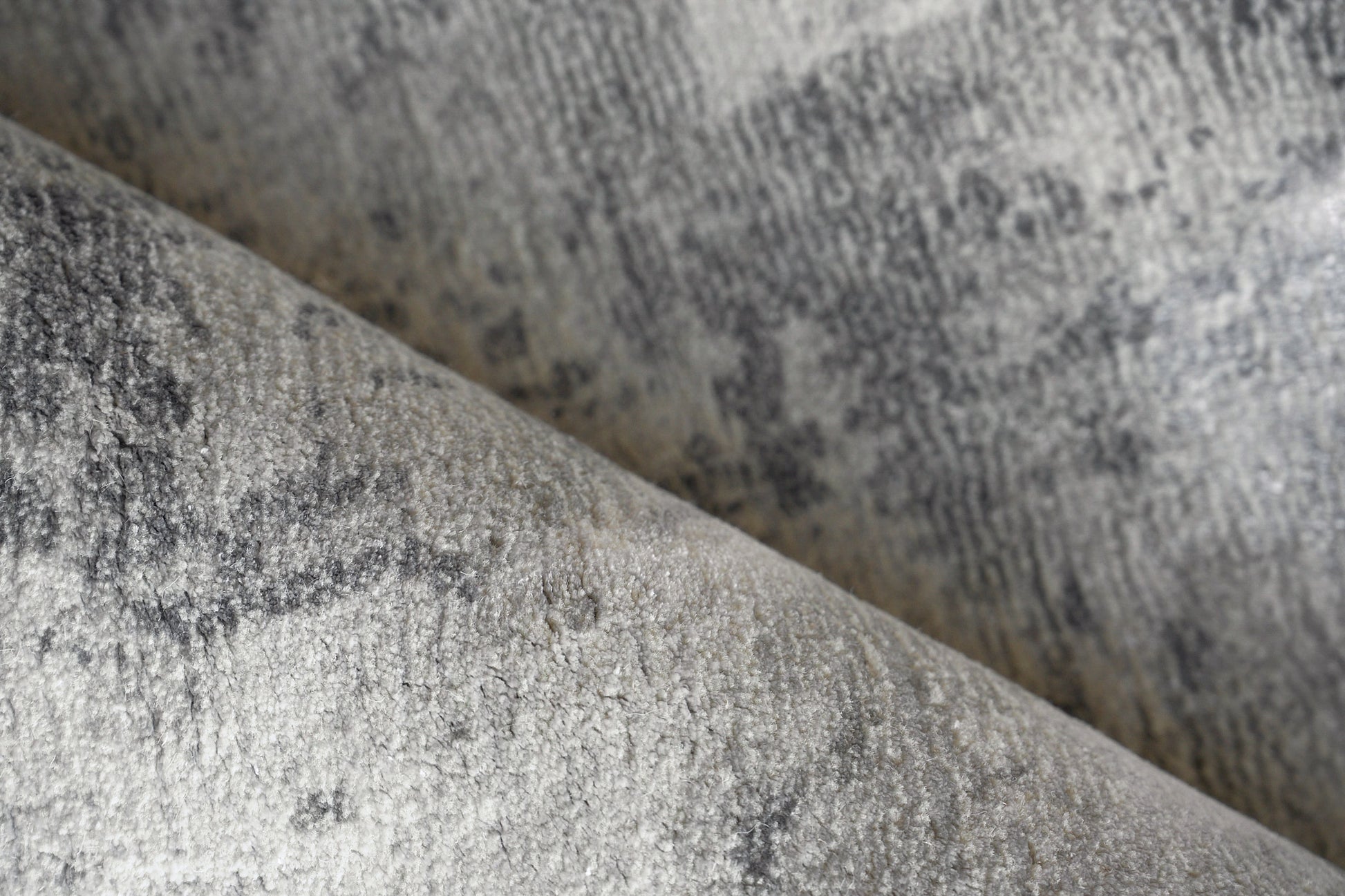 Close-up of plush gray velvet-like rug pile with a mottled pattern on an indoor hand-loomed rug.