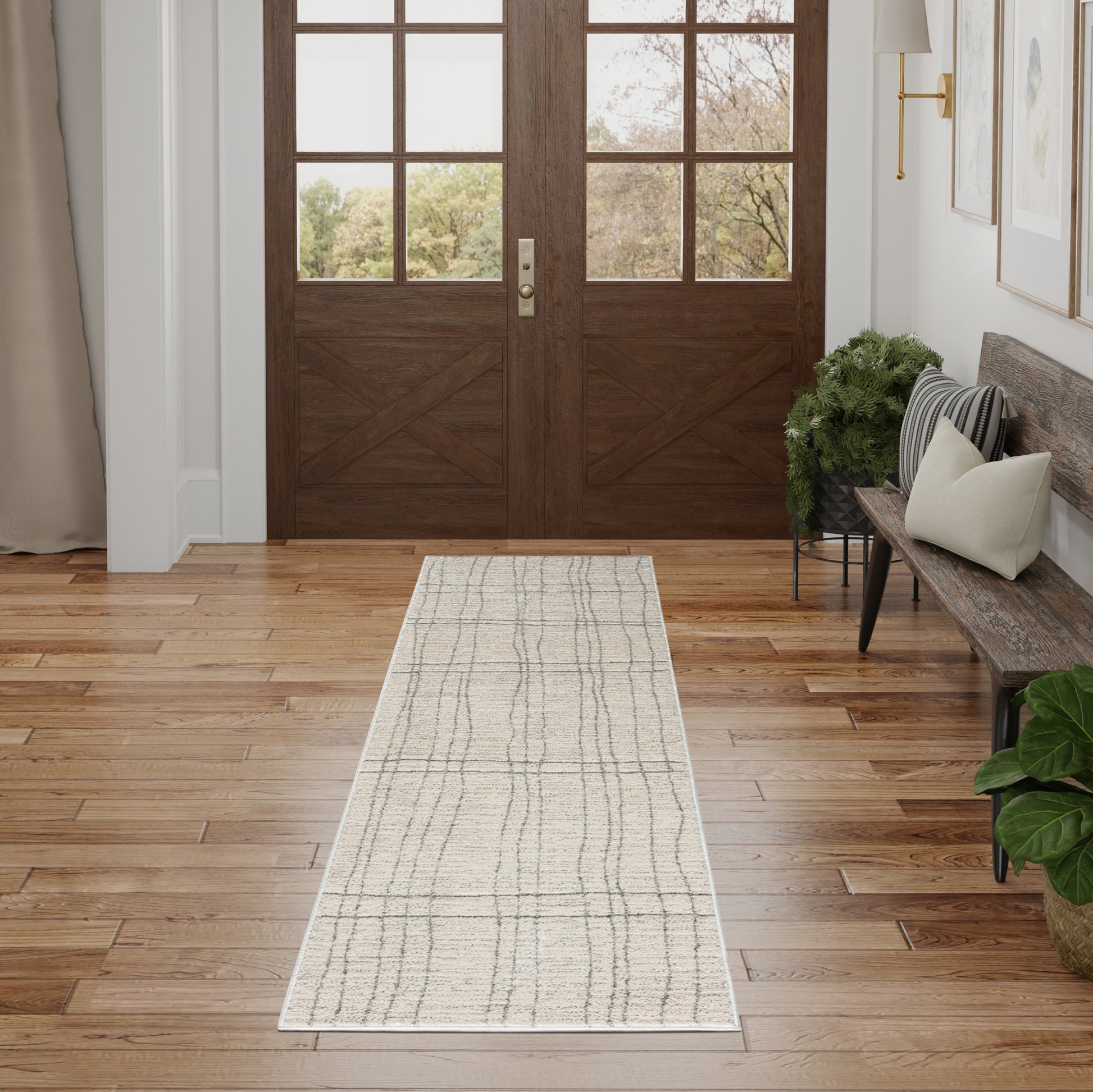 Beige hallway runner rug with gray grid lines on hardwood floor in front of wooden double doors, with a bench nearby.