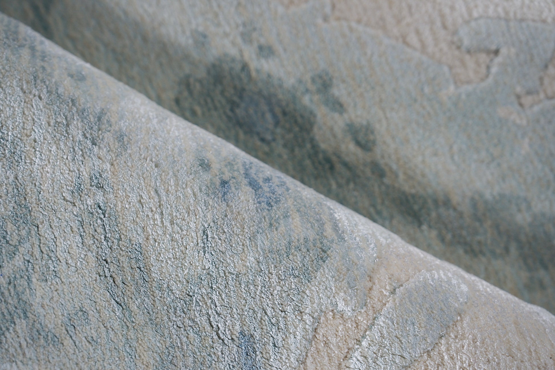 Close-up of blue-gray and beige textured textile with a subtle marbled pattern and soft pile; rug.