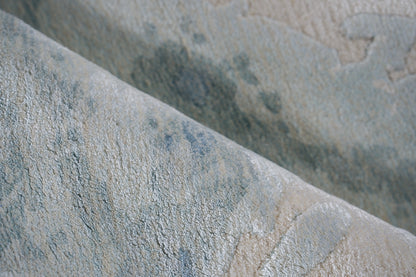 Close-up of blue-gray and beige textured textile with a subtle marbled pattern and soft pile; rug.
