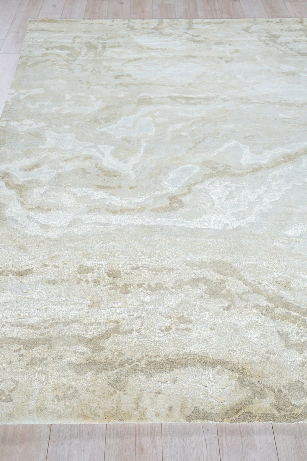 Cream marbled area rug with pale beige swirls on light wood floor