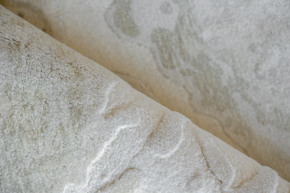Close-up of a pale white rug with soft gray veining and a textured, wrinkled surface; indoor hand-loomed rug.